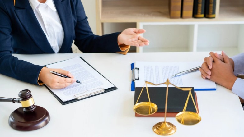 Personal Injury lawyer reviewing case documents with client at desk.